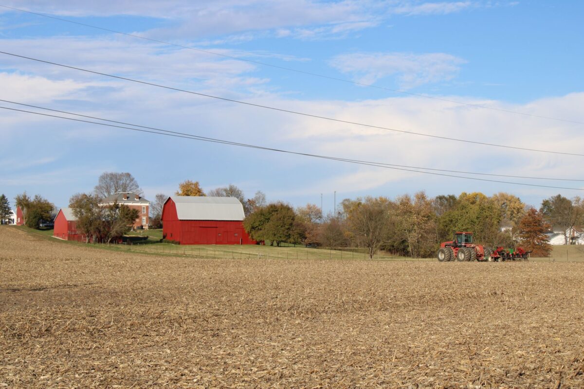 Rustic Ohio farm scene with distinctive red barn and tractor under a bright blue sky.